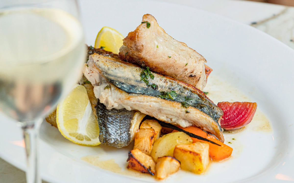 Baked cod fillet served with roasted potatoes, lemon and herbs