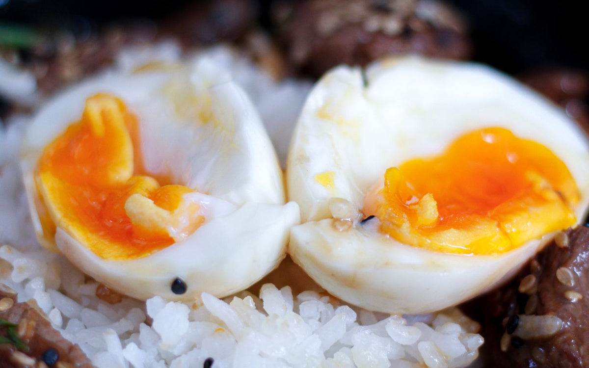 A rice bowl topped with halved soft-boiled eggs and sesame seeds