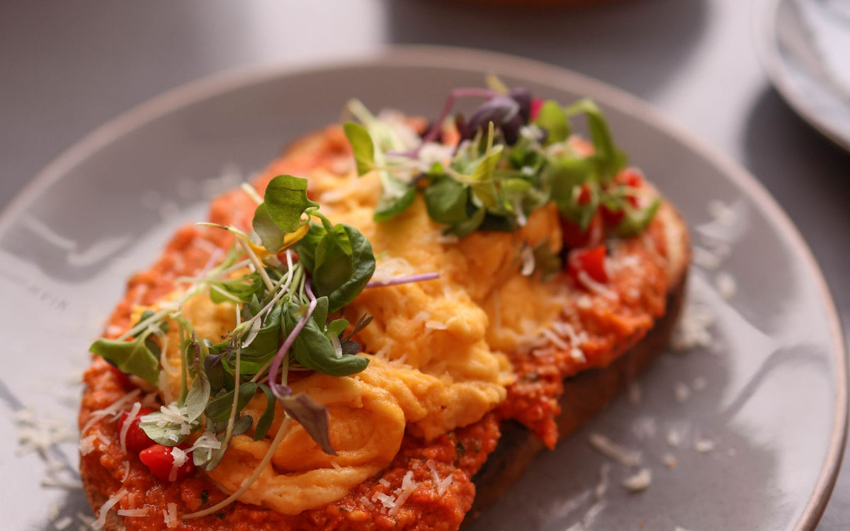 Soft scrambled eggs piled on thick toasted sourdough with fresh herbs