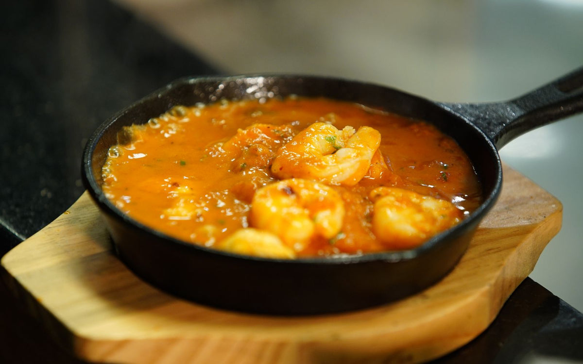 Shrimp simmering in a tomato and bean stew in a cast iron skillet