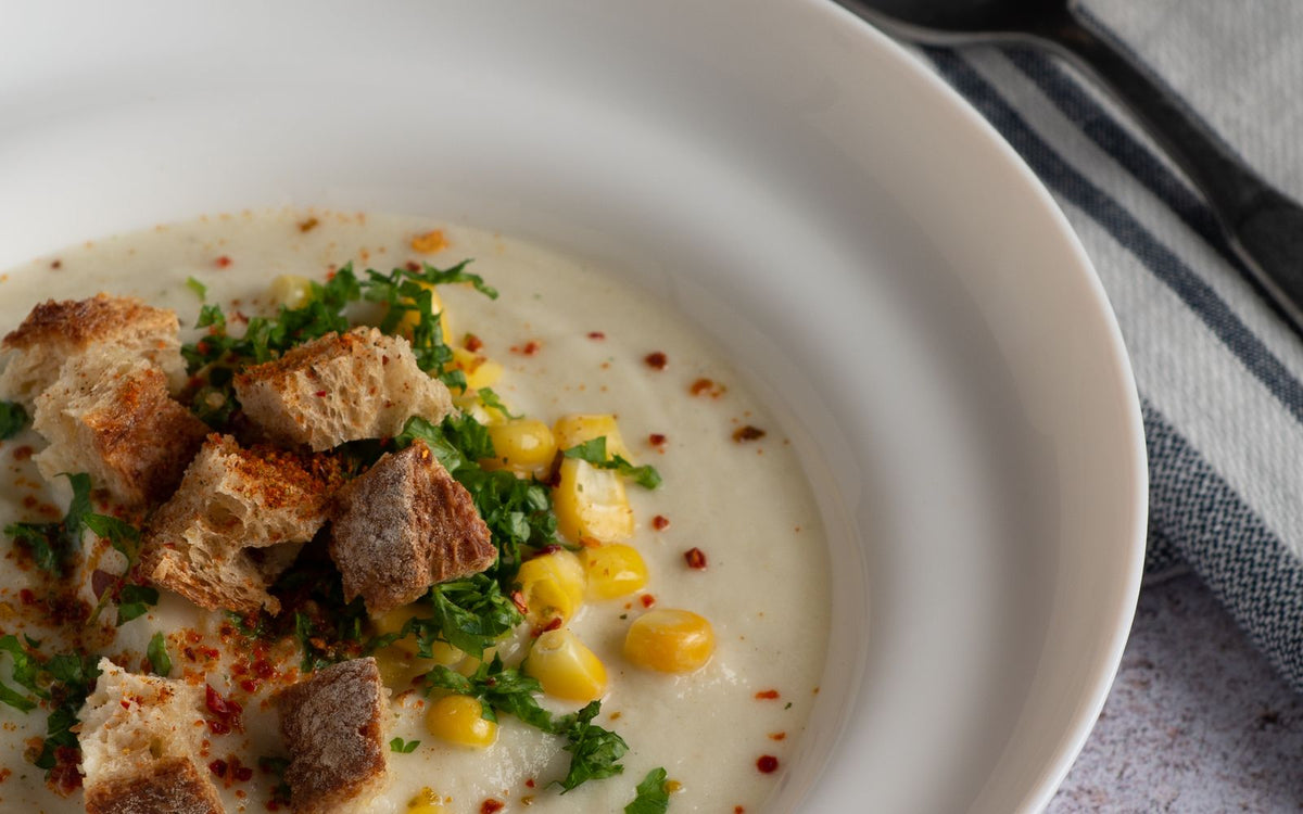 Creamy chowder with sweet corn, parsley and croutons in a white bowl