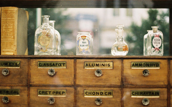 Antique wooden apothecary cabinet filled with labeled glass bottles and drawers
