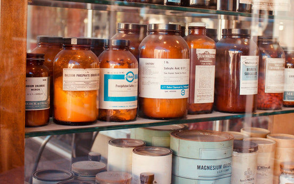 A collection of vintage pharmacy bottles on wooden shelves, showcasing old medicine containers
