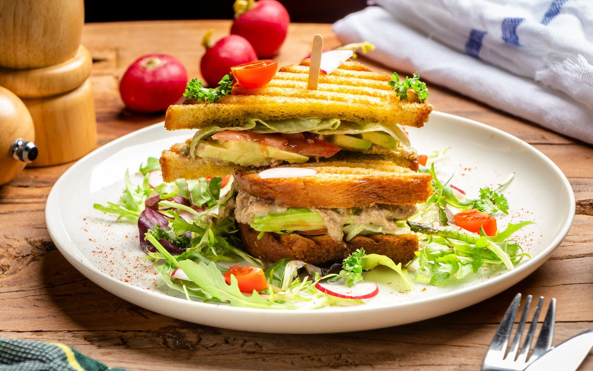 An open tuna sandwich on sourdough with fresh vegetables