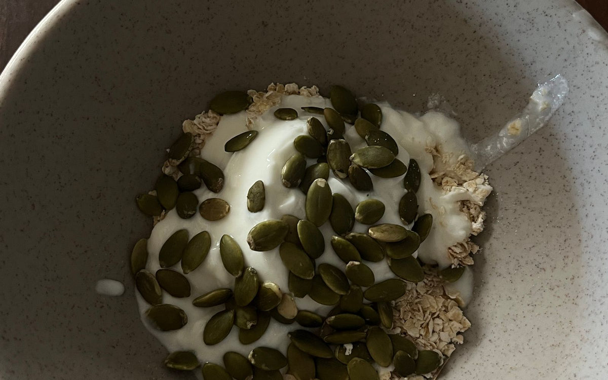 A bowl of thick Greek yogurt topped with oats and seeds