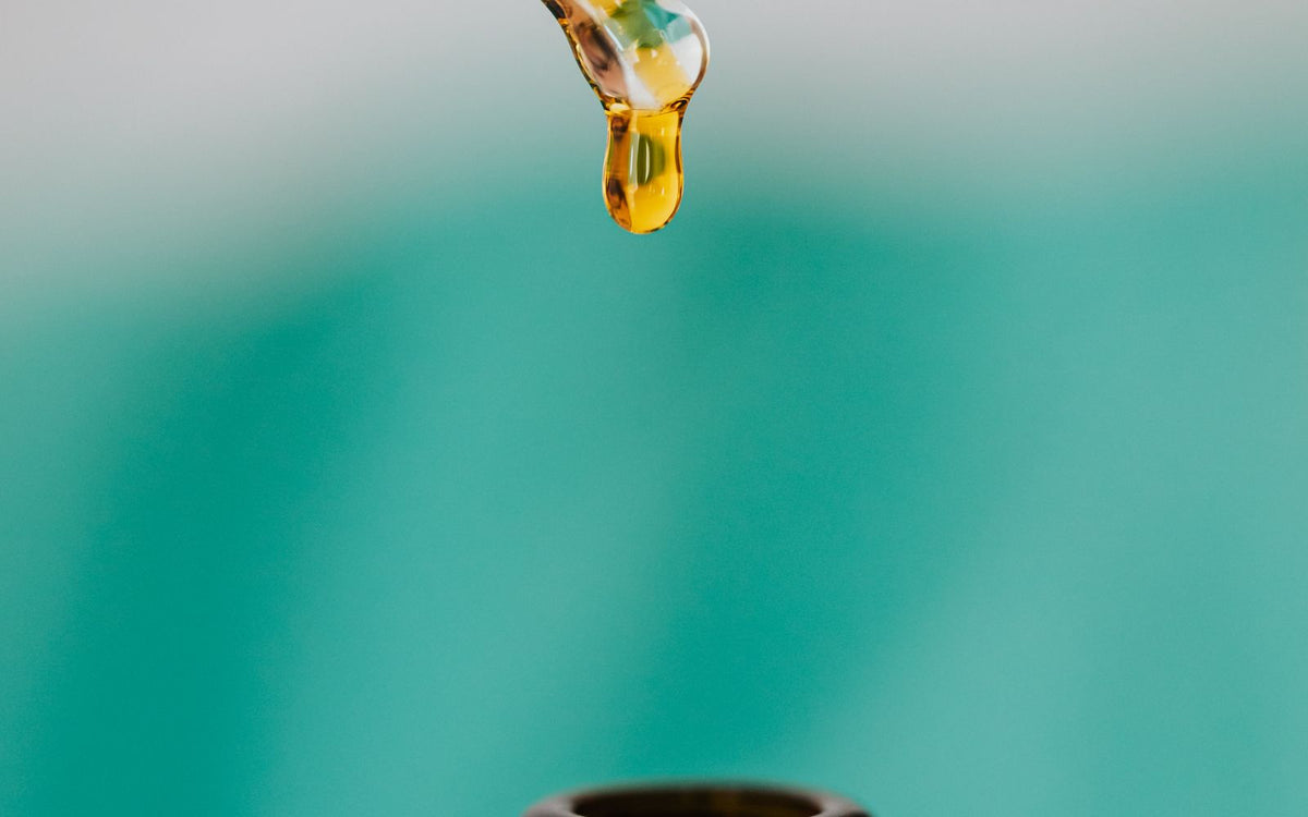 A dropper carefully adding liquid into a brown glass bottle