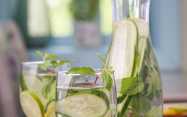 A refreshing detox drink with cucumber, lemon, and mint leaves in a glass pitcher