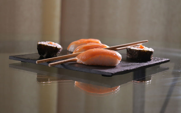 Appetizing salmon nigiri and maki sushi arranged with chopsticks on a slate serving plate