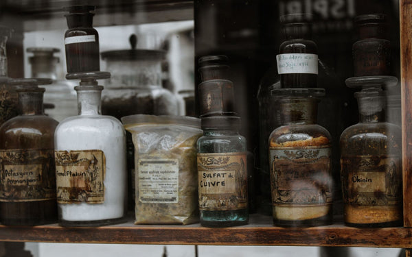 Collection of vintage apothecary bottles with handwritten labels on a wooden shelf