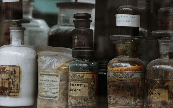 A collection of vintage apothecary bottles and jars on a rustic wooden shelf