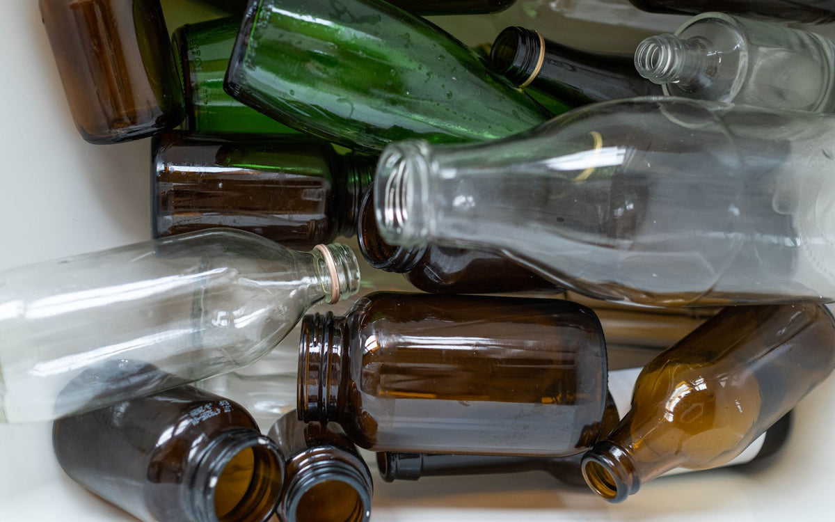 Assorted recyclable glass bottles in green, brown, and clear colors ready for reuse