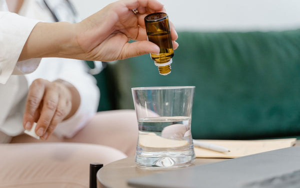 Hand using a dropper to add drops into a glass of water