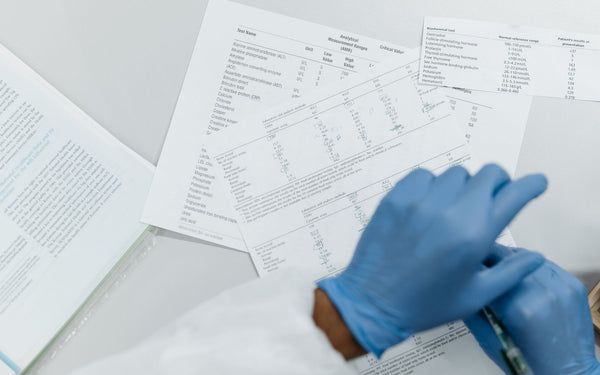 Close-up of gloved hands reviewing printed lab test results