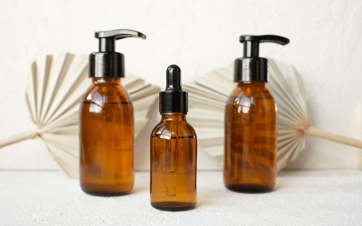 Three amber glass bottles with black caps in a minimalist display, ideal for supplement comparison