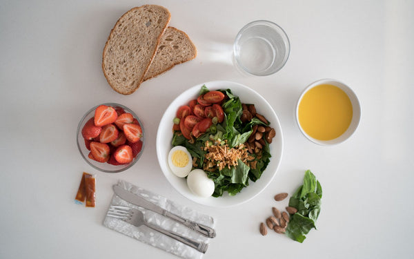 Top view of a nutritious breakfast with salad, eggs, bread, and juice